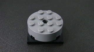 Lego kostička kulatá s kulatou středovou dírou a otočnou černou destičkou - tmavě šedá - dark bluish gray